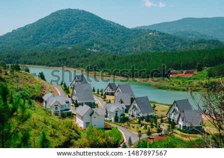 Landscape photo of a small, beautiful and quiet European style villas resort on the bank of Tuyen Lam lake, Dalat, Vietnam. Outdoor picture on a sunny day with clear sky and mountains background