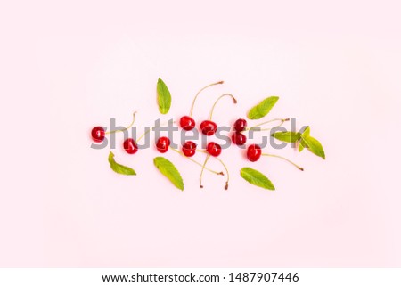 Flat lay of cherries and leaves on a pink background. Minimalism, flat lay, top view, design.