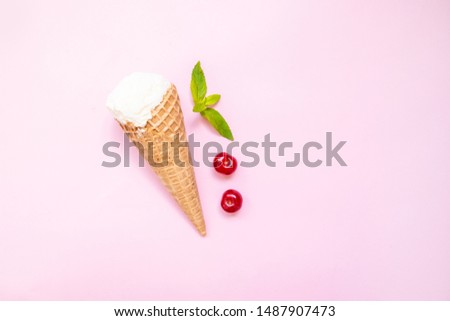 Mint vanilla ice cream with in a waffle cone with mint leaves and ripe cherry berries on a pink plain background. Minimalism, flat lay, top view, design. Summer concept.