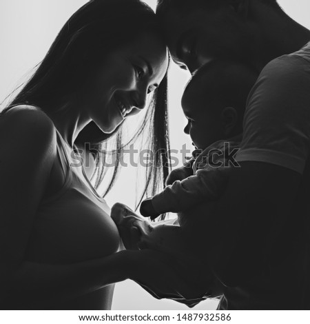 Black and white picture of a young couple with a newborn baby in their hands