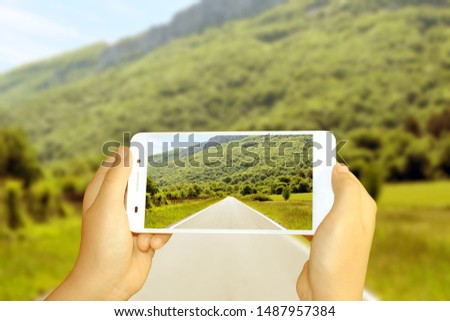 hands with mobile making photo of the road in the bush Royalty-Free Stock Photo #1487957384