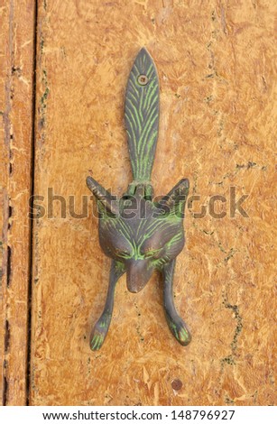 Old metal door handle knocker on wooden background 