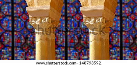 Carved Corinthian capitals from a medieval cloister with background of stained glass, France 