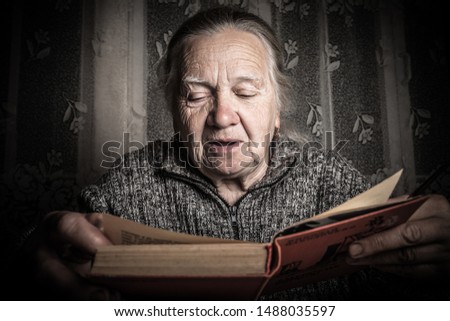 Elderly woman reads book in rustic interior. Toned.