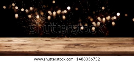 Holiday background with wooden counter and golden firework on night sky