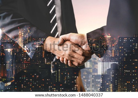 Double exposure image of business people handshake on city office building in background showing partnership success of business deal. Concept of corporate teamwork, trust partner and work agreement. Royalty-Free Stock Photo #1488040337