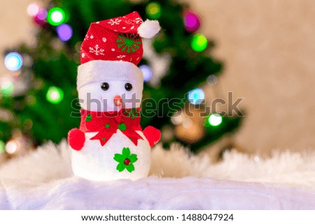 Toy snowman in a red hat near the Christmas tree