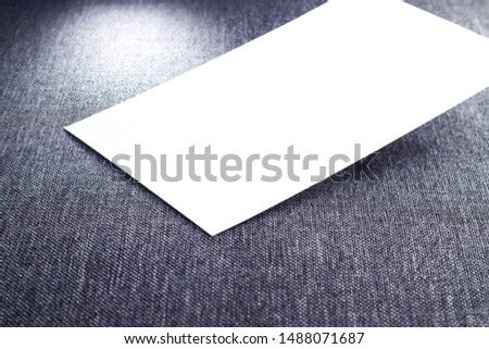 Close up blank paper, white empty business card, poster or flyer on gray fabric texture. Blank signboard with copy space area for text or slogan