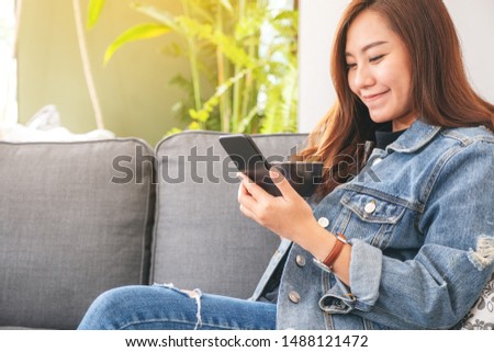 Closeup image of a beautiful asian woman holding and using smart phone while drinking coffee