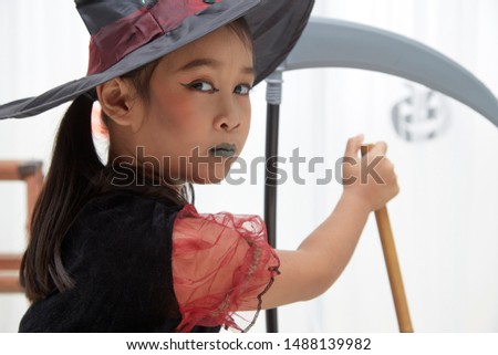 Happy Halloween. little beautiful girl in a witch costume celebrates a home in an interior with pumpkins