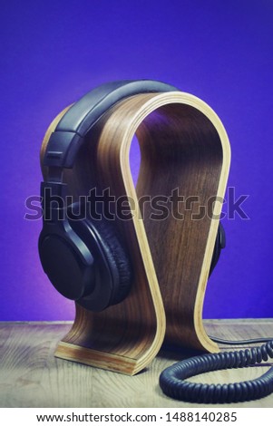Headphones on a wooden stand. A vertical music template, photo, ideal for podcasts or webinars
