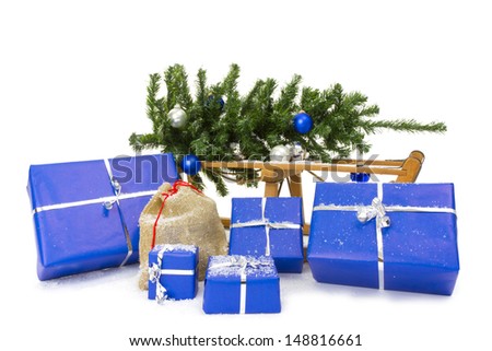 Christmas gifts in snow - Studio. Background you see a sledge and a christmas tree