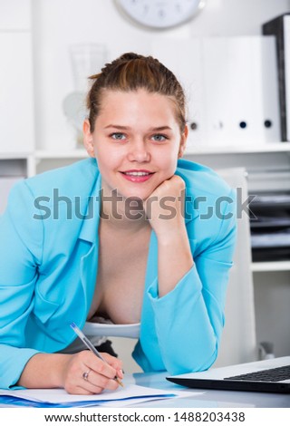 Office worker woman is signing agreement papers of financial nature at office.