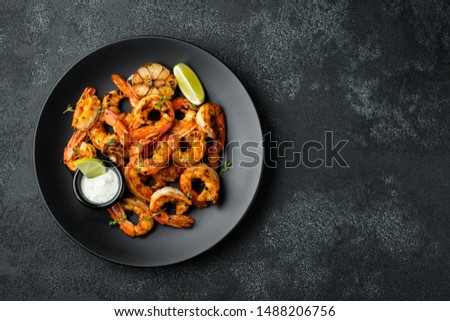 Grilled shrimps or prawns served with lime, garlic and white sauce on a dark concrete background. Seafood. Top view with copy space. Flat lay Royalty-Free Stock Photo #1488206756