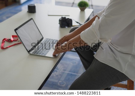 Man's hands using laptop with blank screen on desk in office.