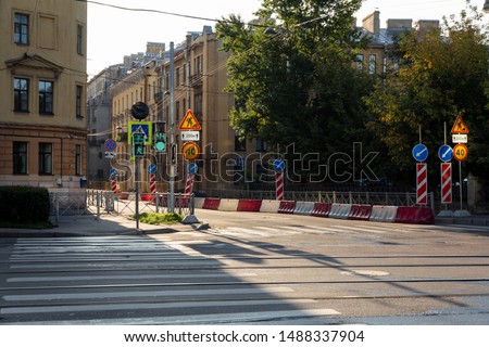 repair of a city road on an early sunny morning at an empty intersection in a residential area with old architecture. working traffic lights and fences in pedestrian areas