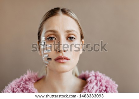 Woman in purple sweater cries and looks into camera. Girl with words on her face is sad