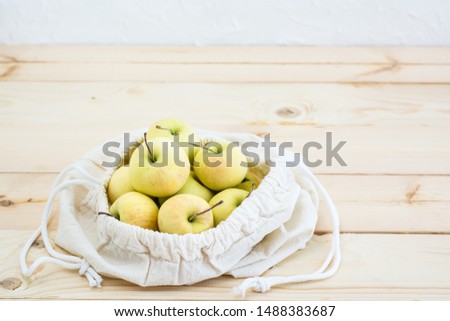 Canvas bag with ties with apples  on a natural wooden background. Zero Waste Concept