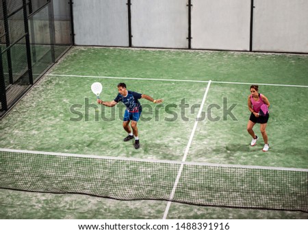 mixed padel match in a green grass padel court indoor behind the net
