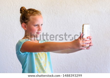 Portrait Of Stylish Girl In Neo Mint Color T-shirt Using Smartphone. Child Teenager Makes Vertical video Or Takes Photo For Story.