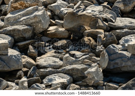 Seamless texture with sea stones and rocks of different sizes as original background. Natural stone of black, gray and brown on the Black Sea coast. Background from really nature
