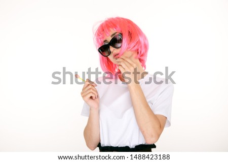 Young pretty girl with pink hair and sweet lollipop isolated in a white studio.