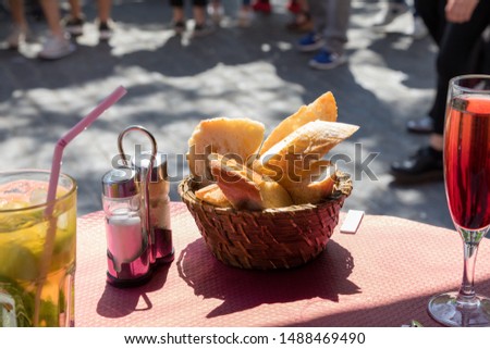 Basket of sliced fresh bread baguette table appetizer restaurant on an outdoor patio with cocktail drinks