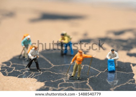 Miniature people : travelers with backpack standing on world map,  exploring on earth background concept.