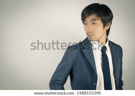 Young Asian Portrait Businessman in Navy Blue Suit Turn Back Pose at Right Frame on Grey Background