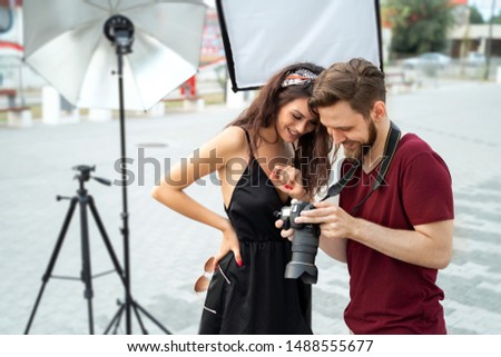 Photographer and female model laughing and looking photos, outdoors set 