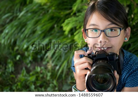 Young little girl photographer with a digital camera taking photo outdoors