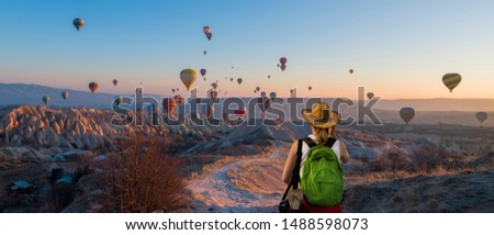 Wonderful Cappadocia skyline at sunrise, flying balloons and tourist girl watching the view