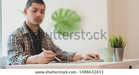 Young professional freelancer planing his project concepts on tablet in comfortable office room 