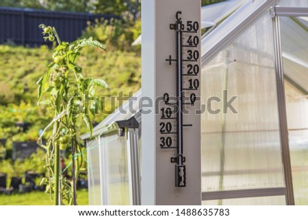 Close up view of outdoor thermometer on white wooden pillar. Beautiful summer backgrounds.