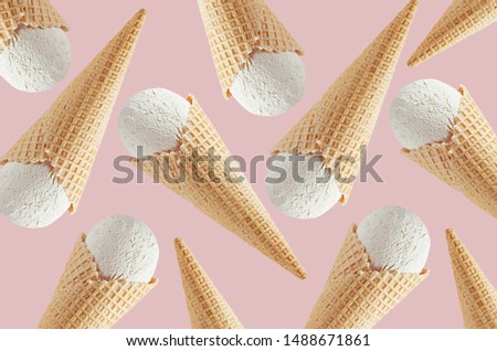 White creamy ice cream in crisp waffle cones as decorative random pattern on soft light pastel pink background.