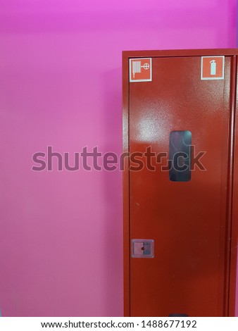Fire cupboard. Red rectangle on the background of the pink wall. Abstract image. Colorful.
 
