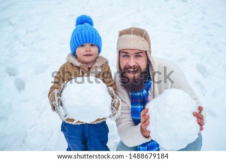 Dad and baby son playing together outdoors. Winter father and son. Happy child playing with snowball against white winter background. Winter scene on white snow background