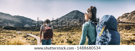 New Zealand Hiking Couple Backpackers Tramping At Tongariro National Park. Male and female hikers hiking by Mount Ngauruhoe. People living healthy active lifestyle outdoors