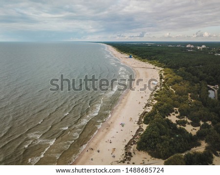 Aerial view of beach in Palanga city, with sand dunes, Baltic sea waves and pine tree forest surrounding.