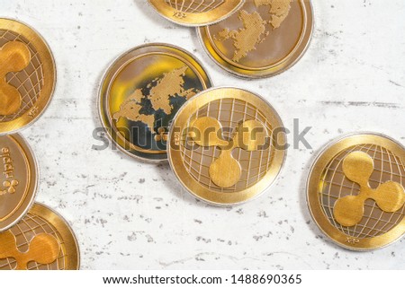 Top down view - golden XRP - ripple cryptocurrency - coins on white stone board