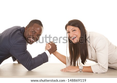 A business man and woman arm wrestling with smiles on their faces.