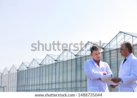 Low angle view of mature male biochemists discussing while standing against clear blue sky