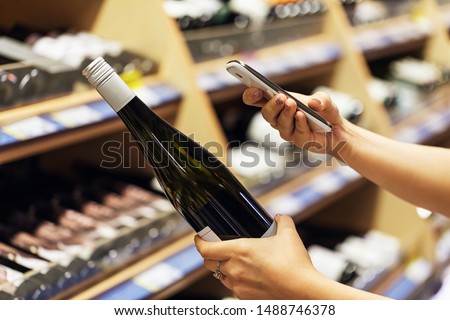 The buyer photographs a bottle of wine, a mystery shopper. Checking the quality of the goods by barcode