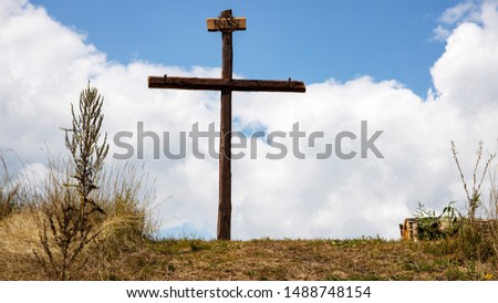 Wood cross on blue sky. The Cross with bright sun and clouds in the background. Christian background.