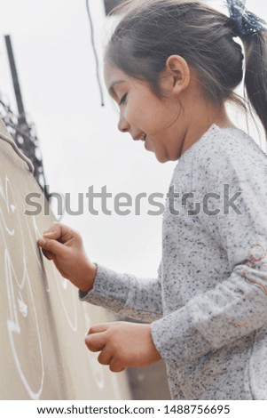 Little latin girl drawing on wall.