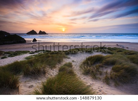 The sun setting over Holywell Bay Beach viewed from the Sand Dunes, Cornwall England UK Royalty-Free Stock Photo #148879130