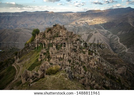 Image of ancient ruins of mountain area with green vegetation against cloudy blue sky