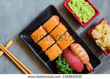 Top view on traditional japanese empty with sushi, ginger, soy sauce, wasabi bowl and chopsticks on concrete grey background, copy space, mockup, flat lay. Online asian food delivery concept