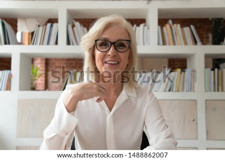 Smiling mature businesswoman sit at desk in office talk with client customer have conversation on webcam, happy positive middle-aged female employee in glasses video call at workplace Royalty-Free Stock Photo #1488862007