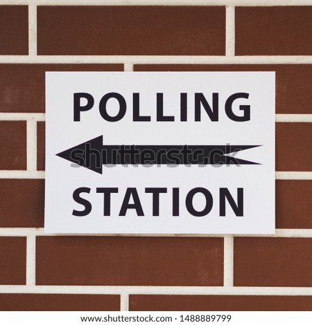 Polling station sign with direction on brick wall close-up